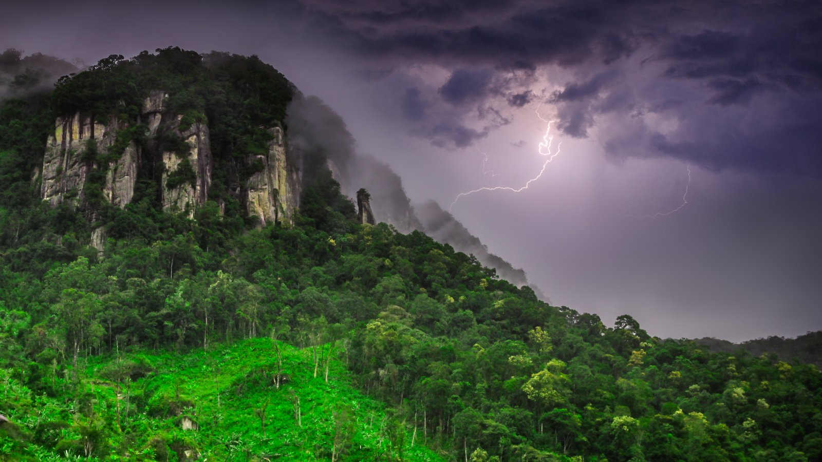 Stunning tropical landscape of Madagascar highlands during a storm with a flash of lighting in the background.